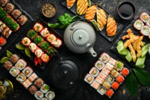 big-set-asian-food-sushi-rolls-traditional-tea-black-stone-background-scaled